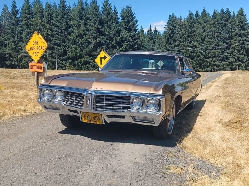 Driver front view of brown 1970 Buick Electra 225 Sedan parked on a wooded gravel road