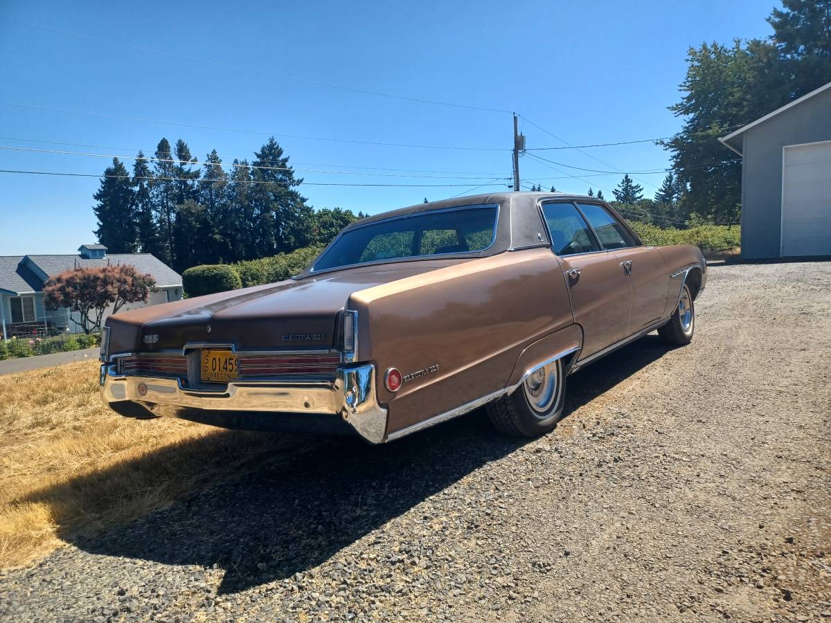 Passenger rear 3q view of brown 1970 Buick Electra parked on a gravel driveway