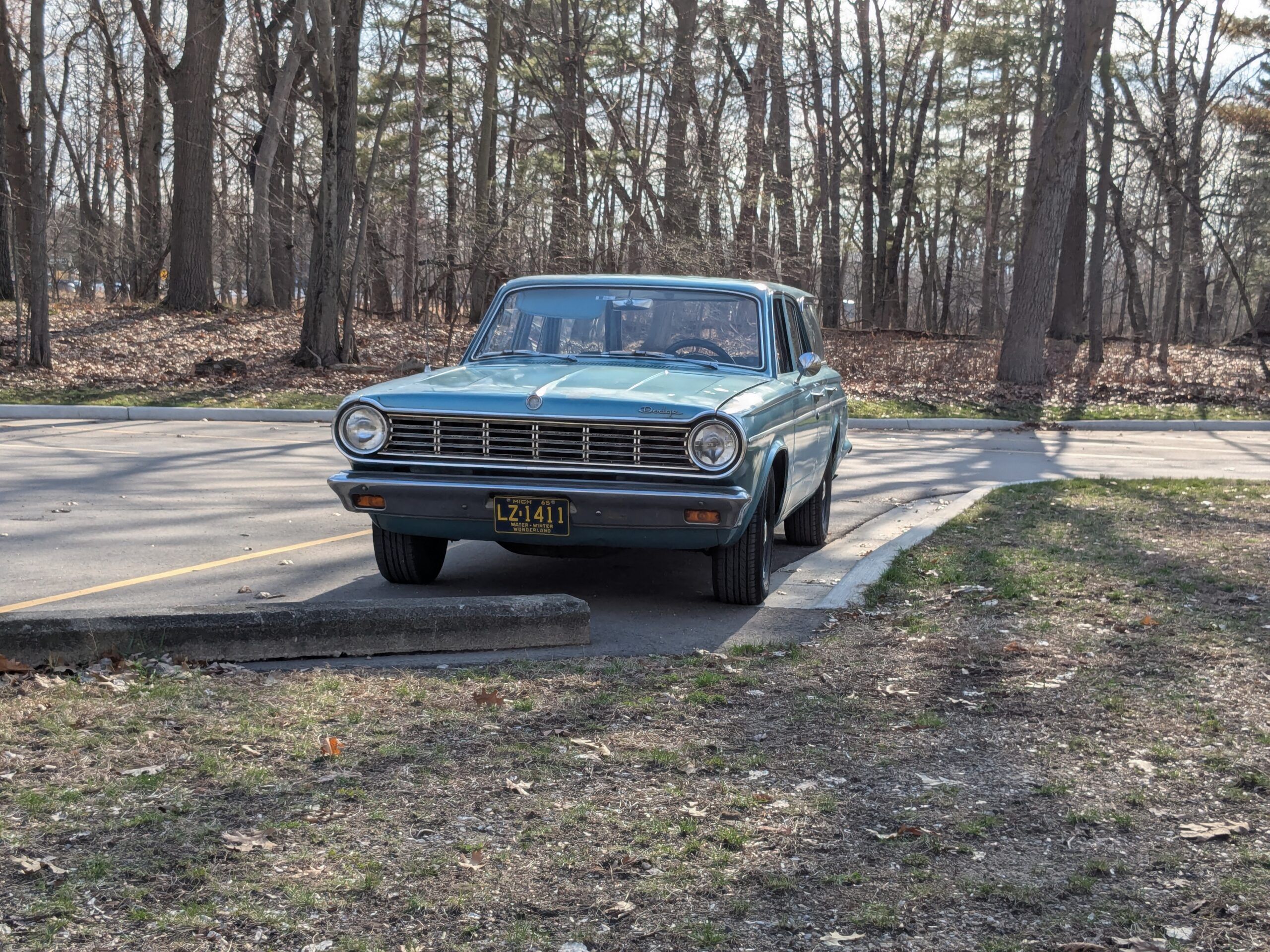 Front view of turquoise 1965 Dodge Dart station wagon in wooded setting