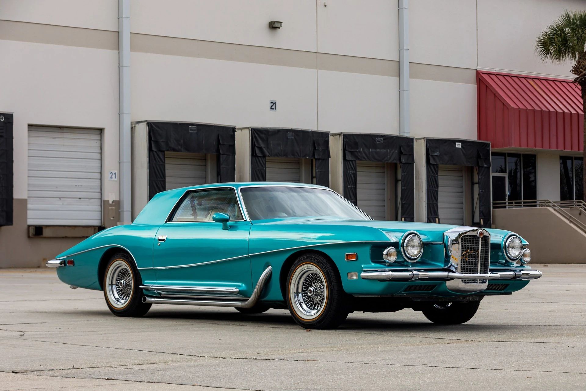 Right front 3q view of a turquoise coupe with a neoclassical grille and side exhaust pipes