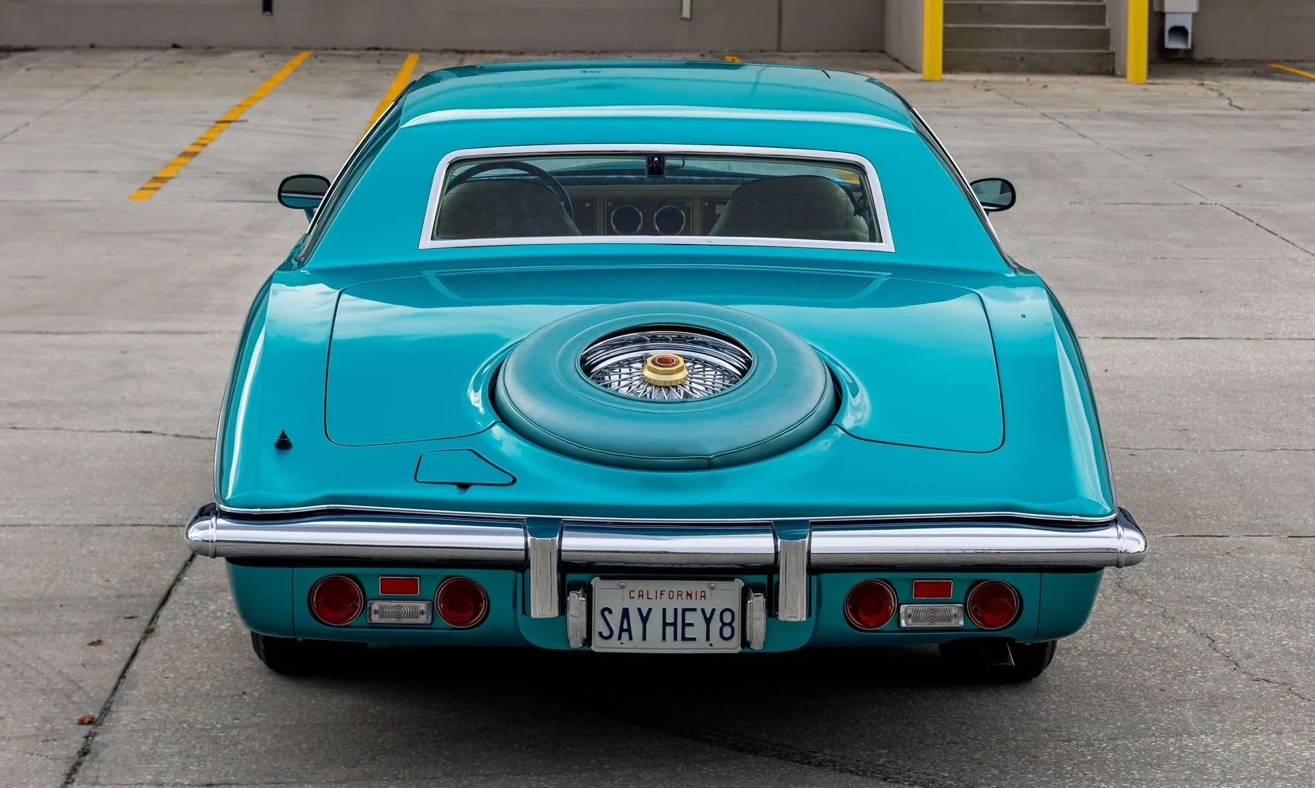 Rear view of a turquoise 1978 Stutz, showing off its exposed spare tire and tiny rear window; the license plate reads "SAY HEY8"