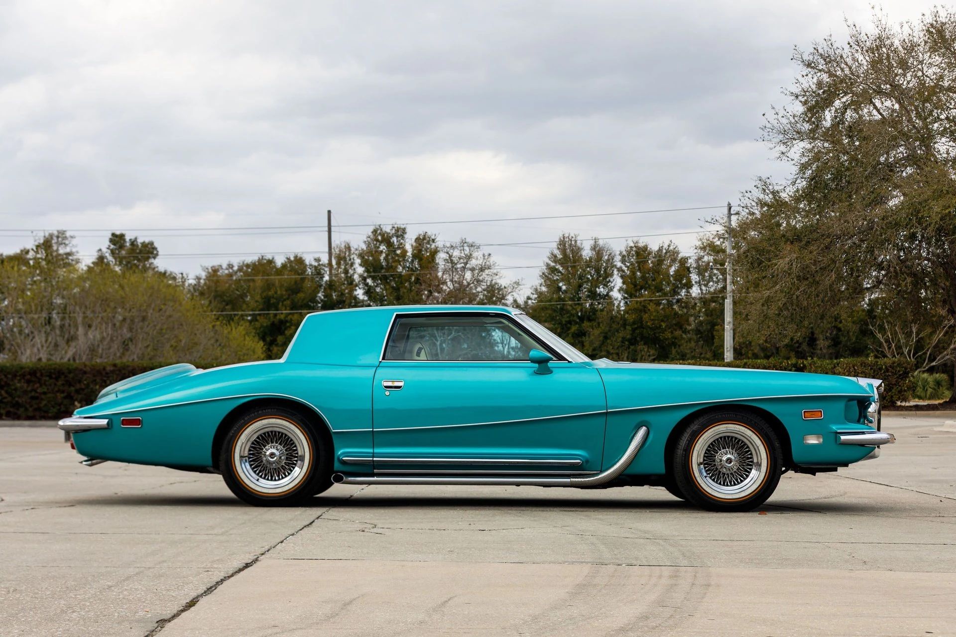 Right side view of a turquoise neoclassical Stutz coupe with wire wheels and fake side pipes