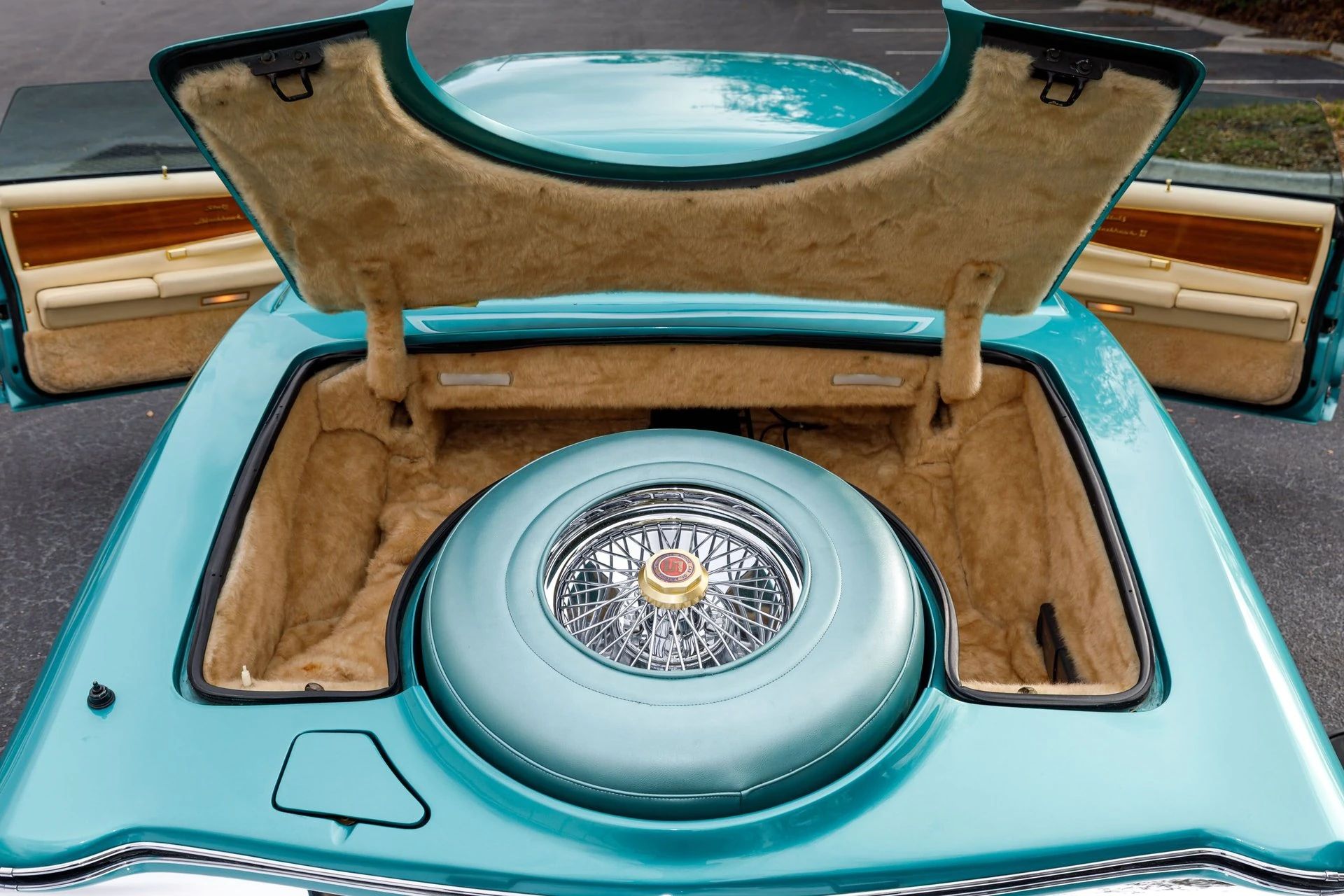 Trunk of a 1978 Stutz, with the spare tire set in a central molding that protrudes through the decklid; the trunk is lined with deep fur-like carpet