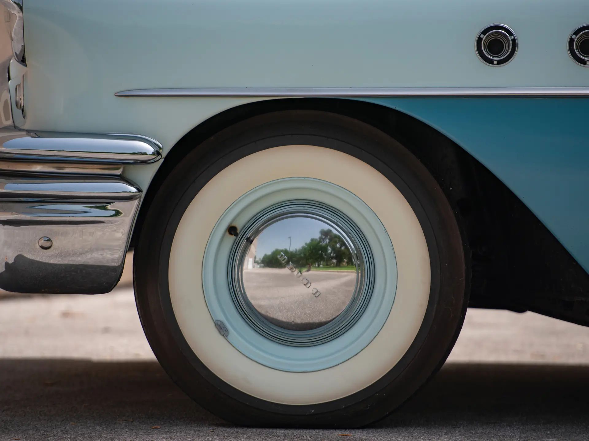 Left front tire of a 1955 Buick, with a wide whitewall tire, but a dog dish hub cap
