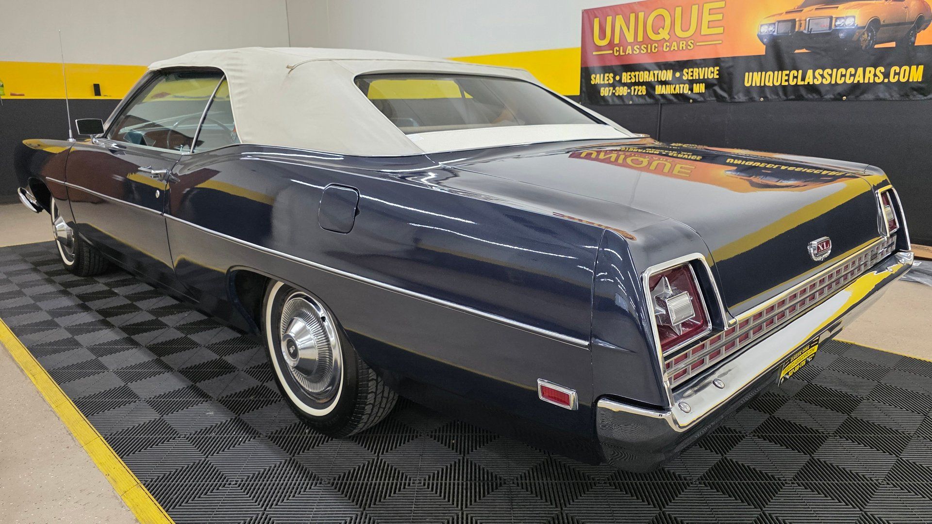 Driver rear 3q picture of dark blue 1969 Ford XL Convertible parked inside a dealership