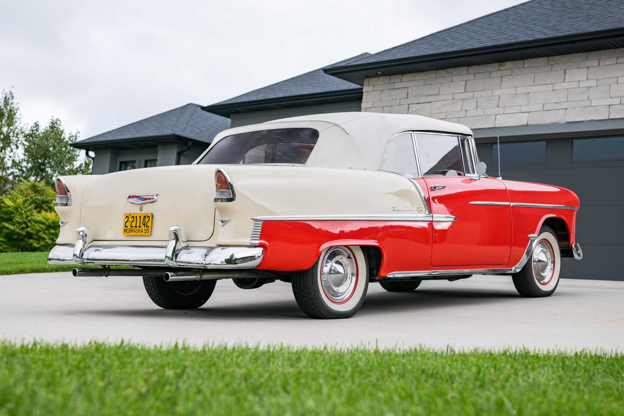 Passenger rear 3q picture of red-and-white 1955 Chevrolet Bel Air Convertible parked in a driveway