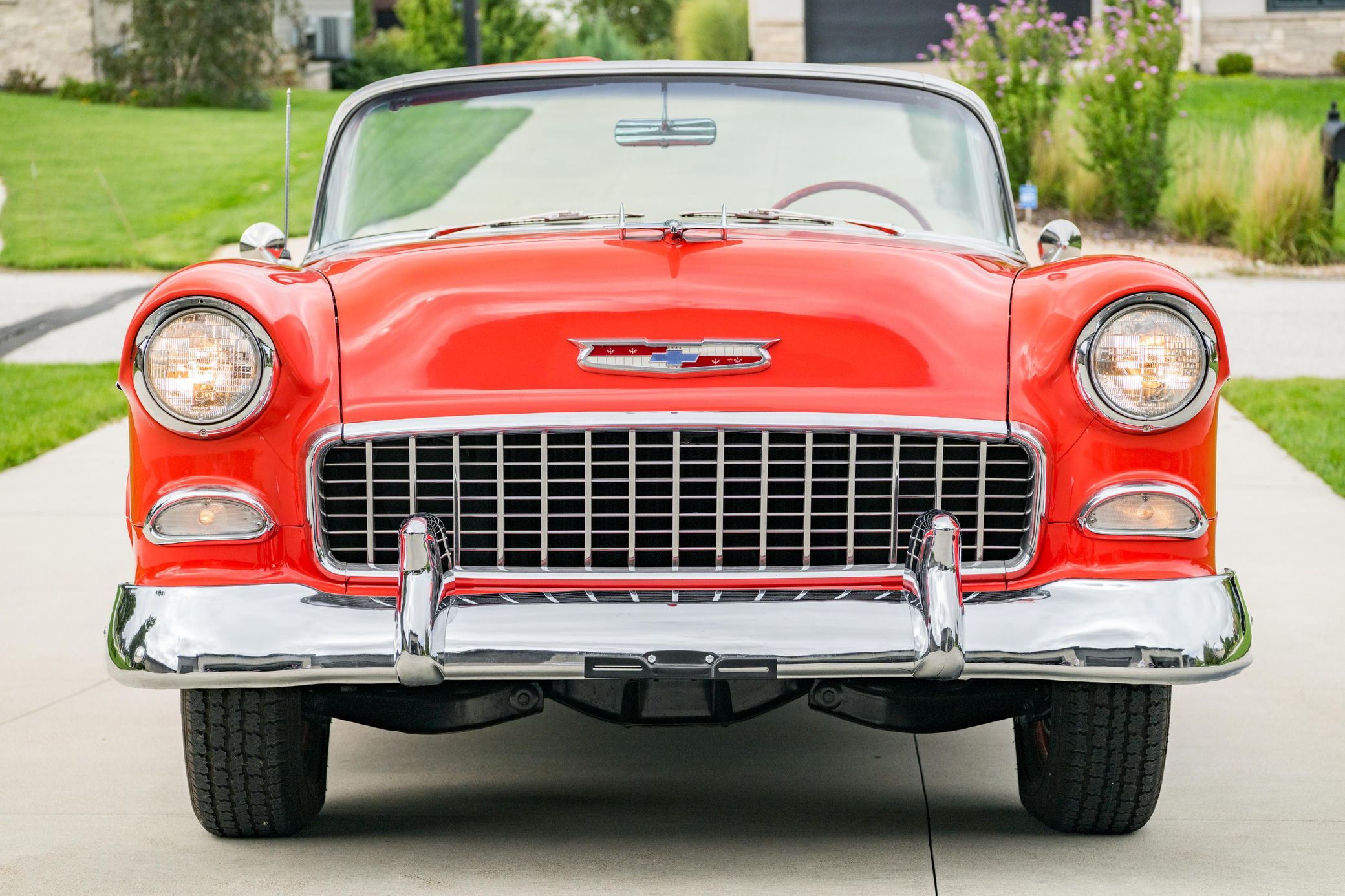 Front view of red-and-white 1955 Chevrolet Bel Air Convertible parked in a driveway