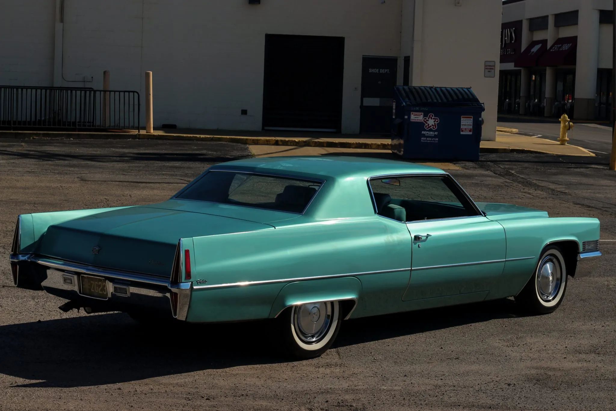 Passenger rear 3q picture of turquoise 1970 Cadillac Calais Coupe parked near a building