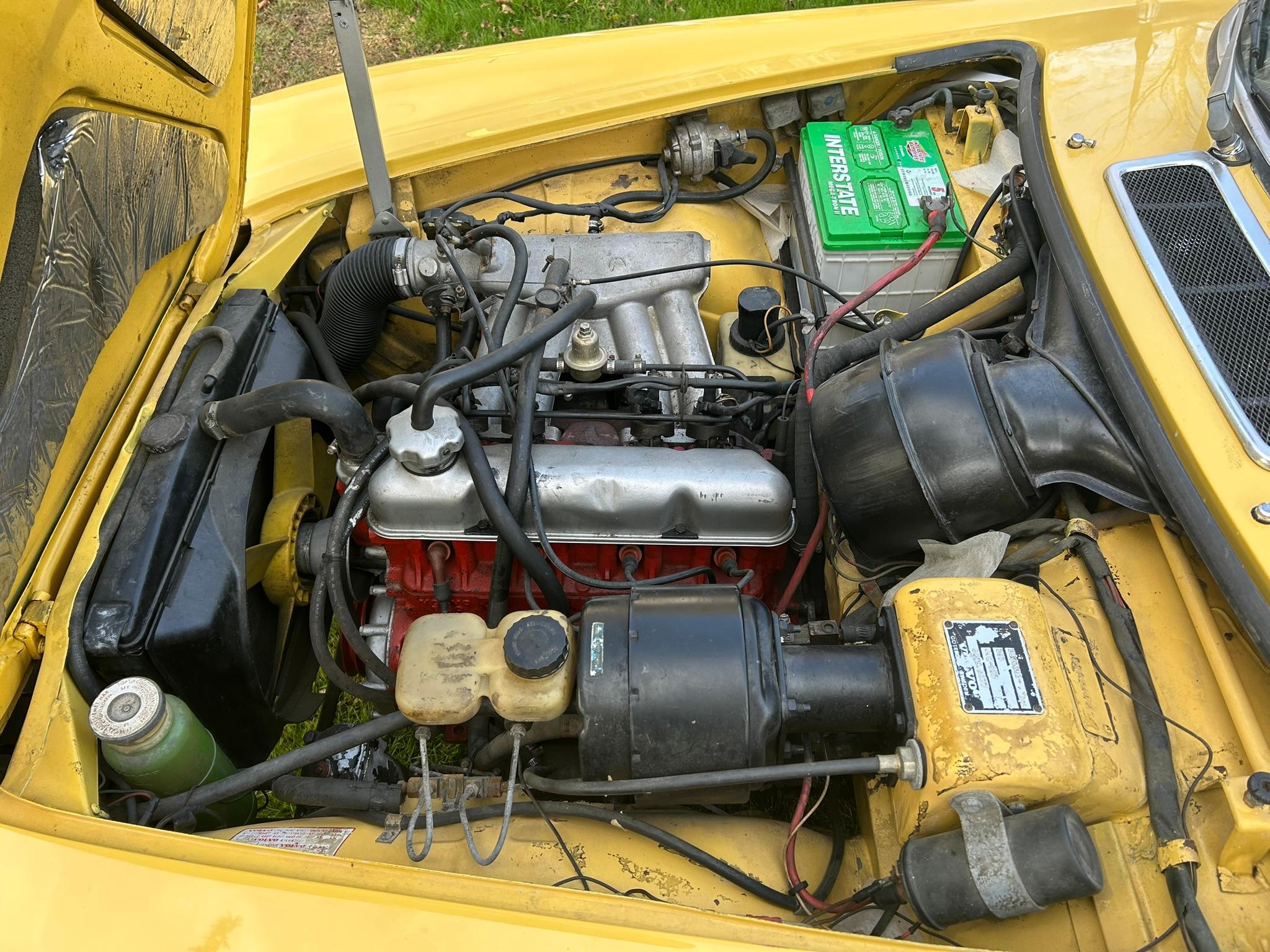 Engine compartment of yellow 1972 Volvo 1800ES with 2.0-liter fuel-injected four-cylinder engine