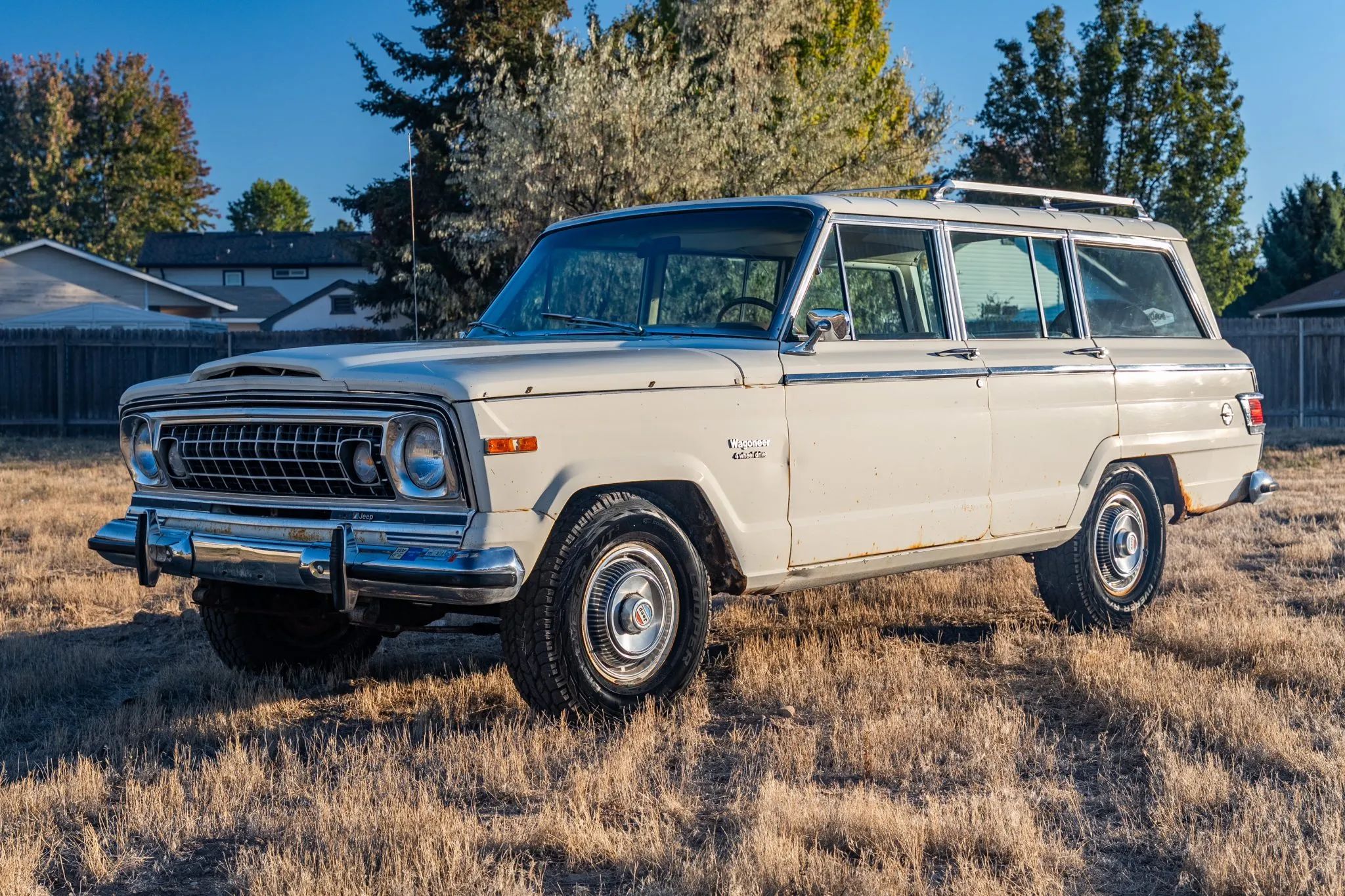 1975 Jeep Wagoneer Custom: A 401-Powered, No-Reserve Example Of America's Greatest Automotive Industrial Design 1 Driver front 3q picture of white 1975 Jeep Wagoneer Custom parked on dried grass facing a sunrise