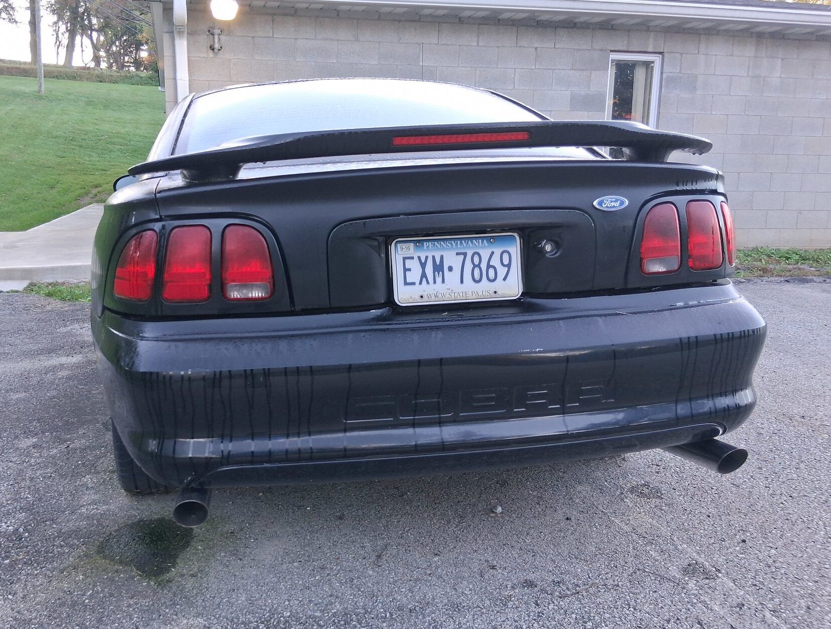 Rear view of black 1996/7 Ford Mustang Cobra in front of a gray block building