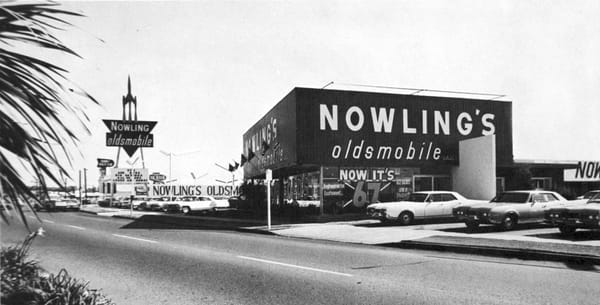 B&W photo of Nowling's Oldsmobile, with window sign reading "Now It's '67"