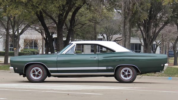 Left side view of a Forest Green 1968 Plymouth GTX hardtop with a white vinyl top and styled road wheels