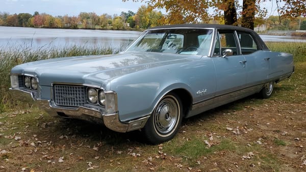 1968 Ford Thunderbird Versus Rivals – How Ford Ranked The T-Bird's Competition 34 Left front 3q view of a Blue Sapphire 1968 Oldsmobile 98 Luxury Sedan with a black vinyl top parked in front of a lake