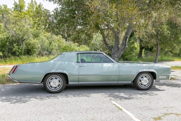 Right side view of a Crystal Firemist 1967 Cadillac Fleetwood Eldorado parked under a tree
