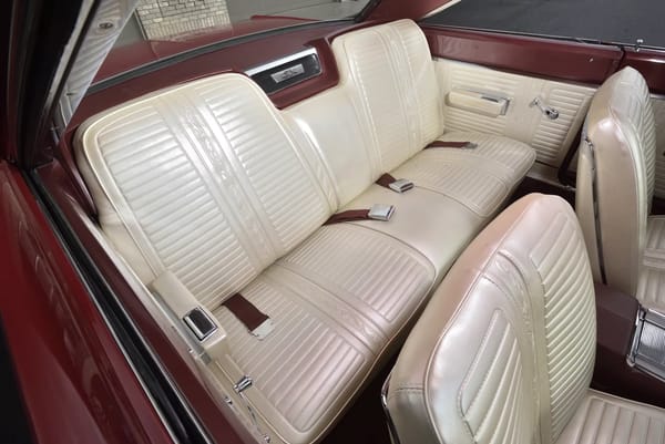 Back seat of a Bright Red 1967 Plymouth GTX with white vinyl upholstery