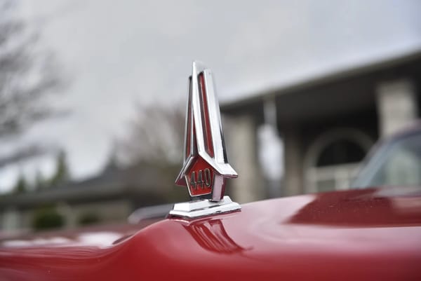 Closeup of the hood ornament (with "440" lettering) on a Bright Red 1967 Plymouth GTX hardtop