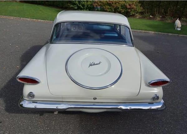 Vintage R&T Review: 1960 Valiant — A Technical Analysis Of Chrysler's New Compact 13 High angle rear view of a white 1960 Valiant, showing the simulated spare tire outline on the rear decklid; there's a dog in the background