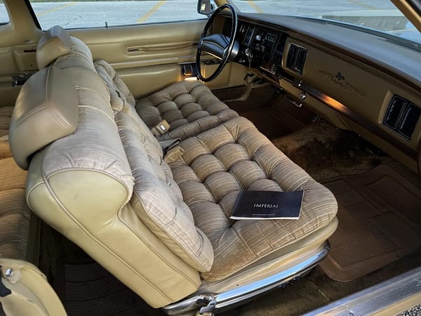 Front seat and dashboard of a 1974 Imperial LeBaron with velour upholstery, seen through the passenger door