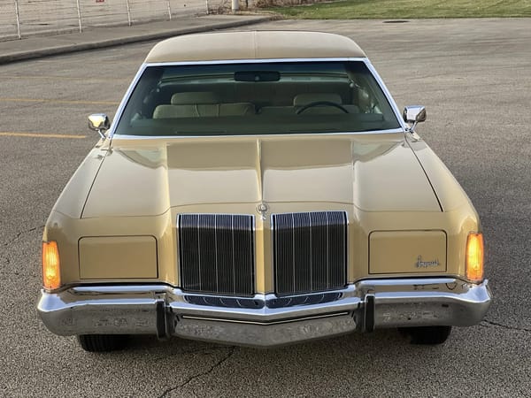 High-angle front view of a gold 1974 Imperial LeBaron, photographed at sunset with the parking lights on