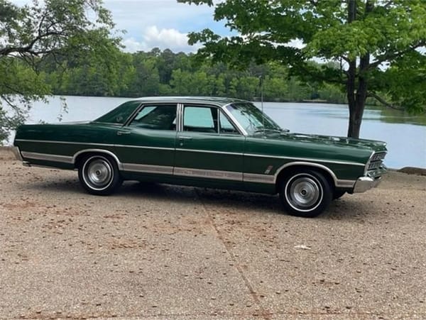 Right side view of a Dark Moss Green 1967 Ford LTD four-door pillared sedan parked in front of a lake